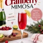 Cranberry Mimosa in a champagne flute with a lime wedge, surrounded by fresh cranberries and champagne