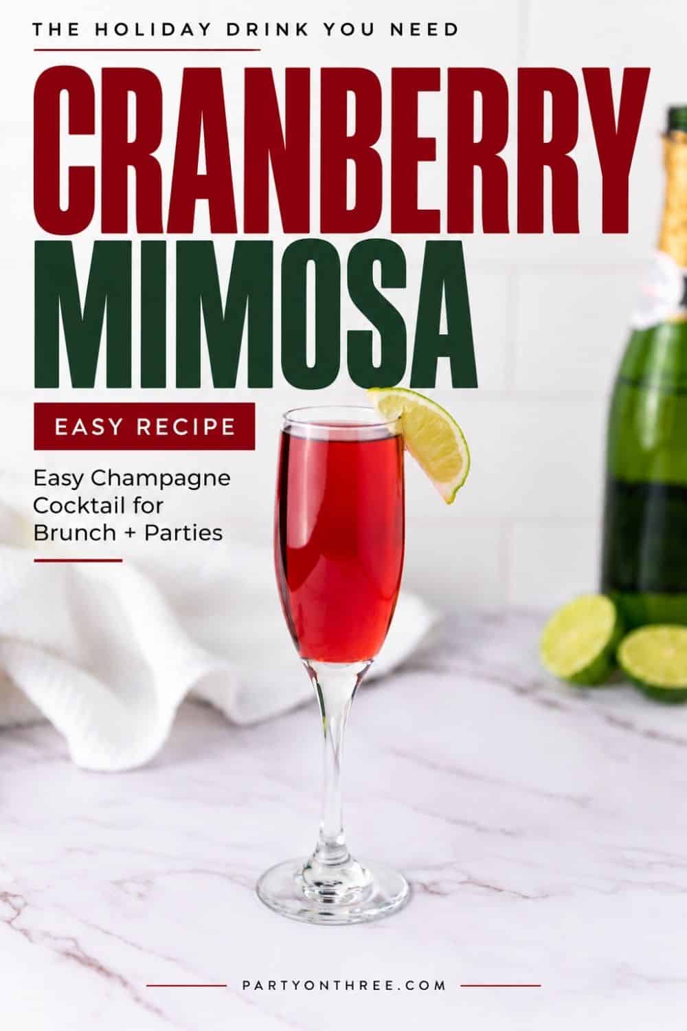 Cranberry Mimosa in a champagne flute with a lime wedge garnish, next to a bottle of champagne