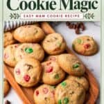 Easy Christmas cookies with red and green M&Ms piled on a wooden board, chocolate chips scattered nearby.