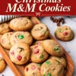 Easy Christmas cookies with red and green M&Ms piled on a wooden board, chocolate chips scattered nearby.