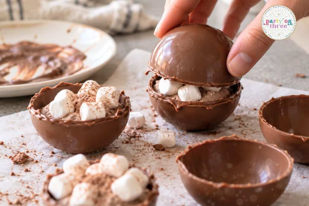 Sealing two chocolate halves together to make a hot cocoa bomb.