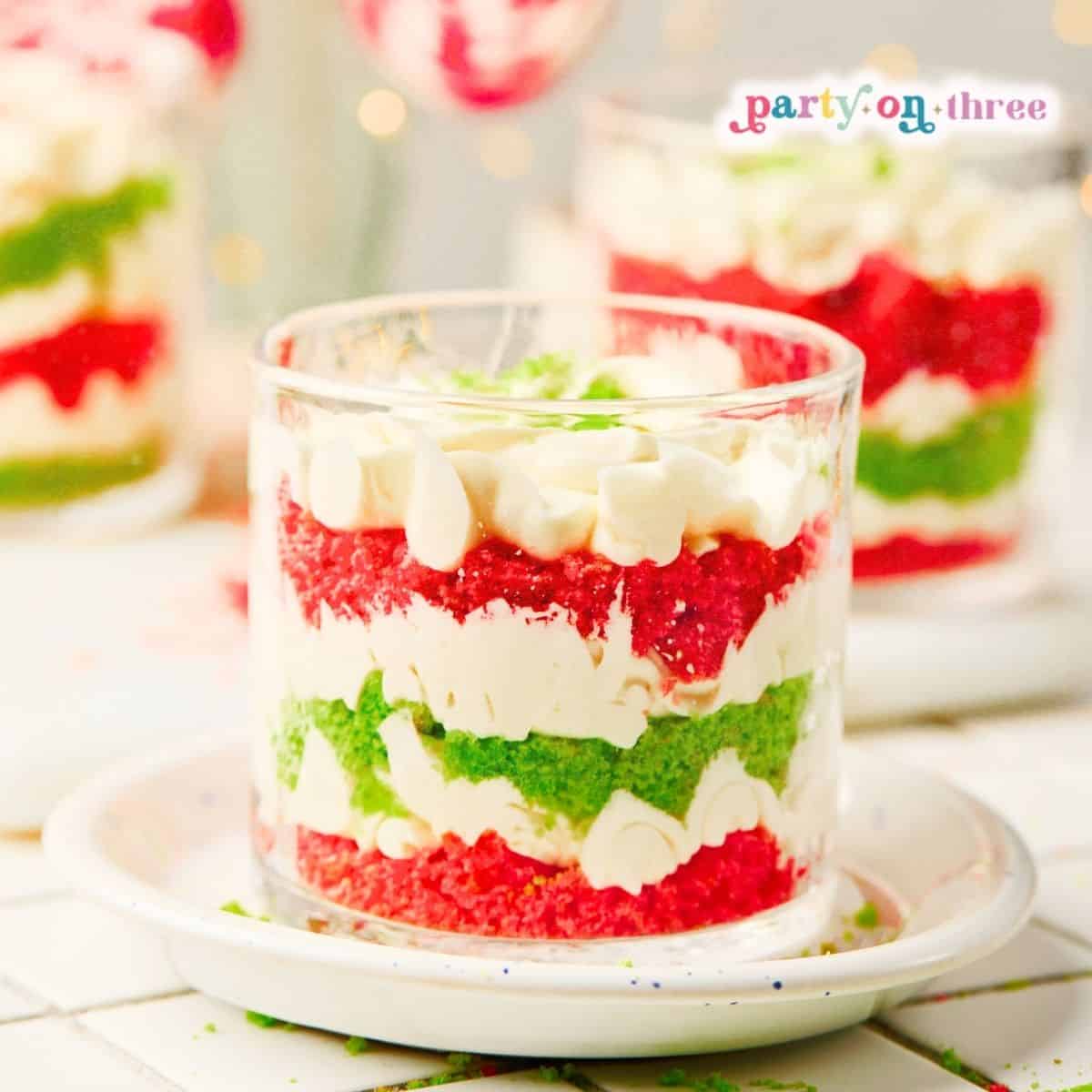 Mini Christmas Trifle Cups with layers of red and green cake, whipped cream, and white chocolate chips