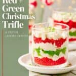 Layered red and green cake crumbs with whipped cream piped in a glass cup on a white plate