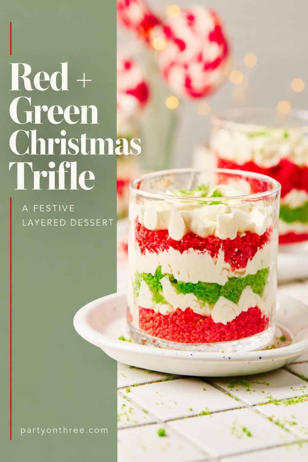 Layered red and green cake crumbs with whipped cream piped in a glass cup on a white plate