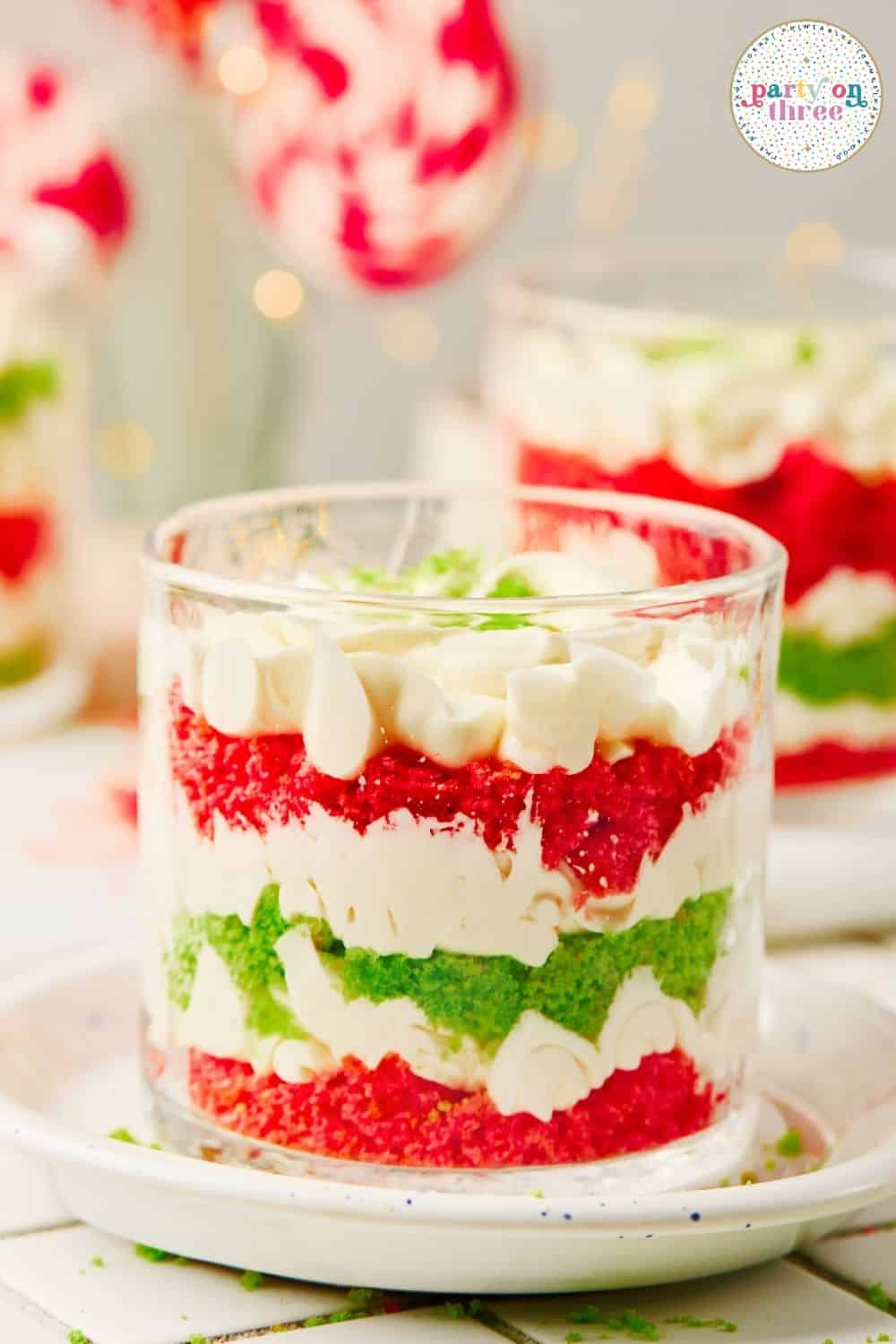 Layered Mini Christmas Trifle Cups with red and green cake crumbs and whipped cream, topped with a piped swirl.