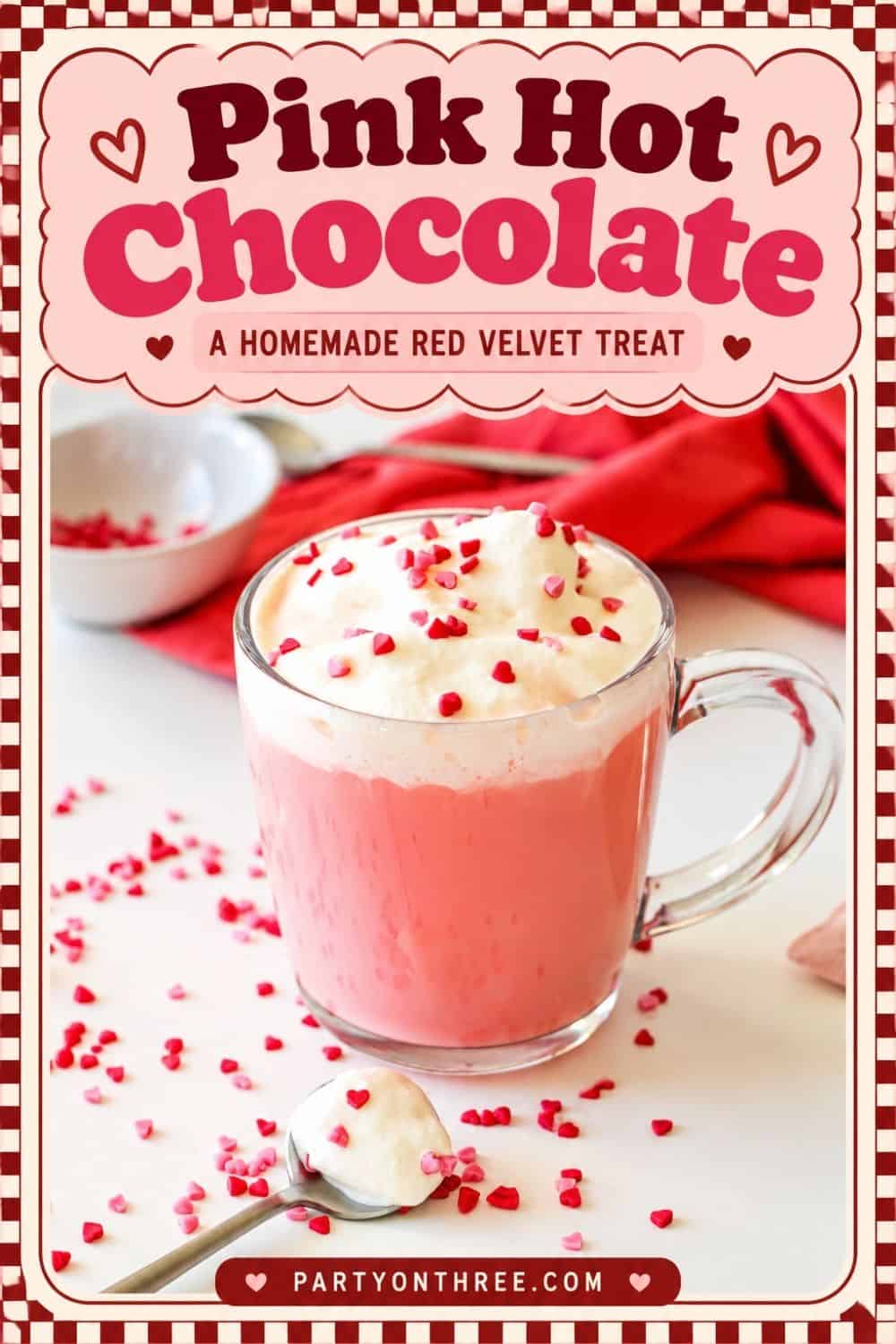 Pink hot chocolate in a glass mug with whipped cream, a homemade red velvet treat