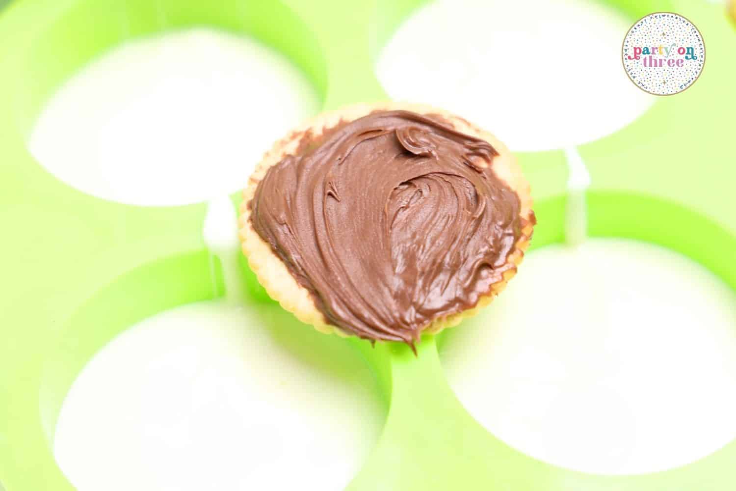Ritz cracker spread with Nutella, resting in a green silicone mold before chilling