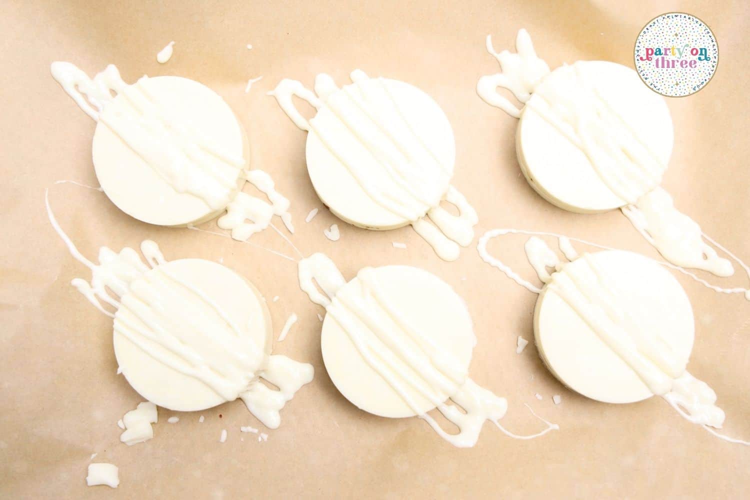 White chocolate-coated Ritz cracker rounds drizzled with white chocolate lines on parchment paper