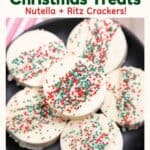 White chocolate-dipped Ritz Cracker Christmas Cookies topped with red, green and white sprinkles on a black plate.